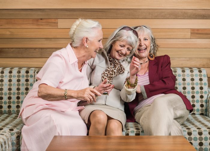 Lifestyle photography by Colin Hawkins of three senior females sitting on a sofa and having fun