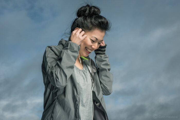 Oriental woman wearing headphones against sky