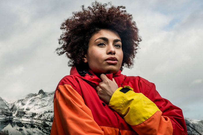 Portrait photograph of a black woman looking cold whilst walking in mountains by photographer Colin Hawkins