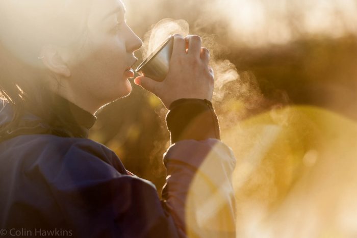 Photography of female canoeist drinking a hot drinking from mug at dawn by photographer Colin Hawkins