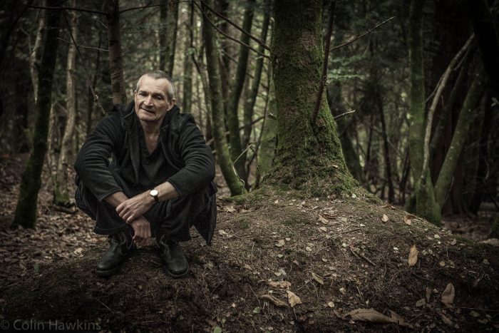 Man squatting down looking lost in woods location portrait photography by Colin Hawkins