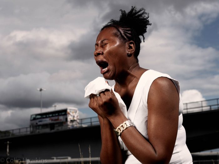 Healthcare photography by Colin Hawkins of a black woman sneezing or having an allergy attack in an urban setting