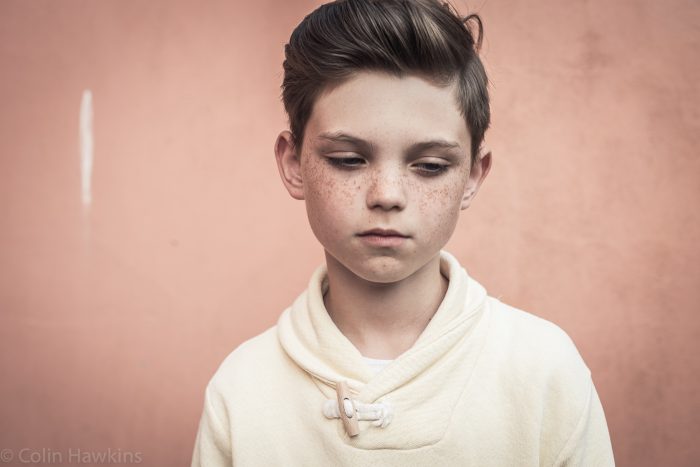 Portrait of young boy against peach wall for healthcare campaign by Colin Hawkins