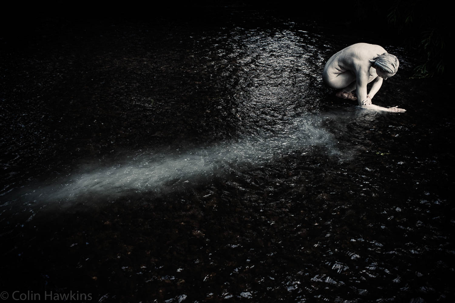 Woman from above washing clay off in river from the Fine Art Photography series by Three Collaborate