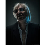 Moody studio portrait photography by Colin Hawkins of a person looking angry in blue light