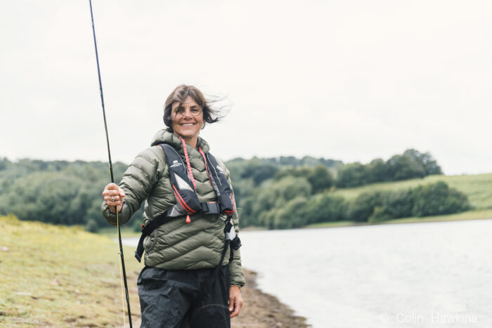 Portrait of a woman fishing at a reservoir holding fishing rod by photographer Colin Hawkins