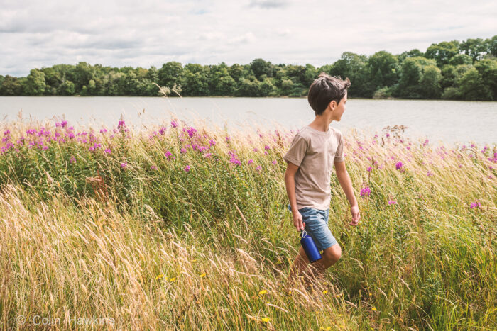 Boy walking whilst looking at reservoir- lifestyle photography by Colin Hawkins