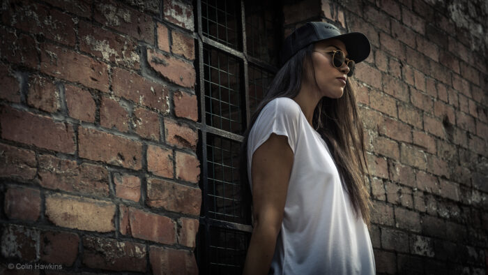 Woman in baseball hat & sunglasses wearing Sportswear in urban setting for Rockstar sports fashion campaign by Colin Hawkins