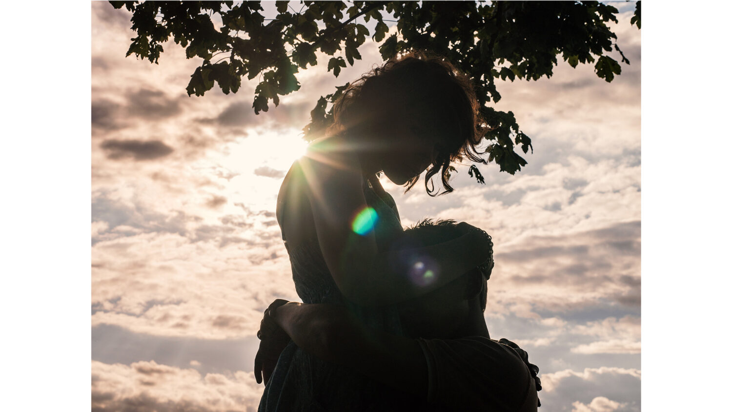 Silhouette of young couple hugging outside at sunset by photographer Colin Hawkins