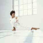 Asian woman exercising in white room with sunlight through windows doing Tai Chi by photographer Colin Hawkins