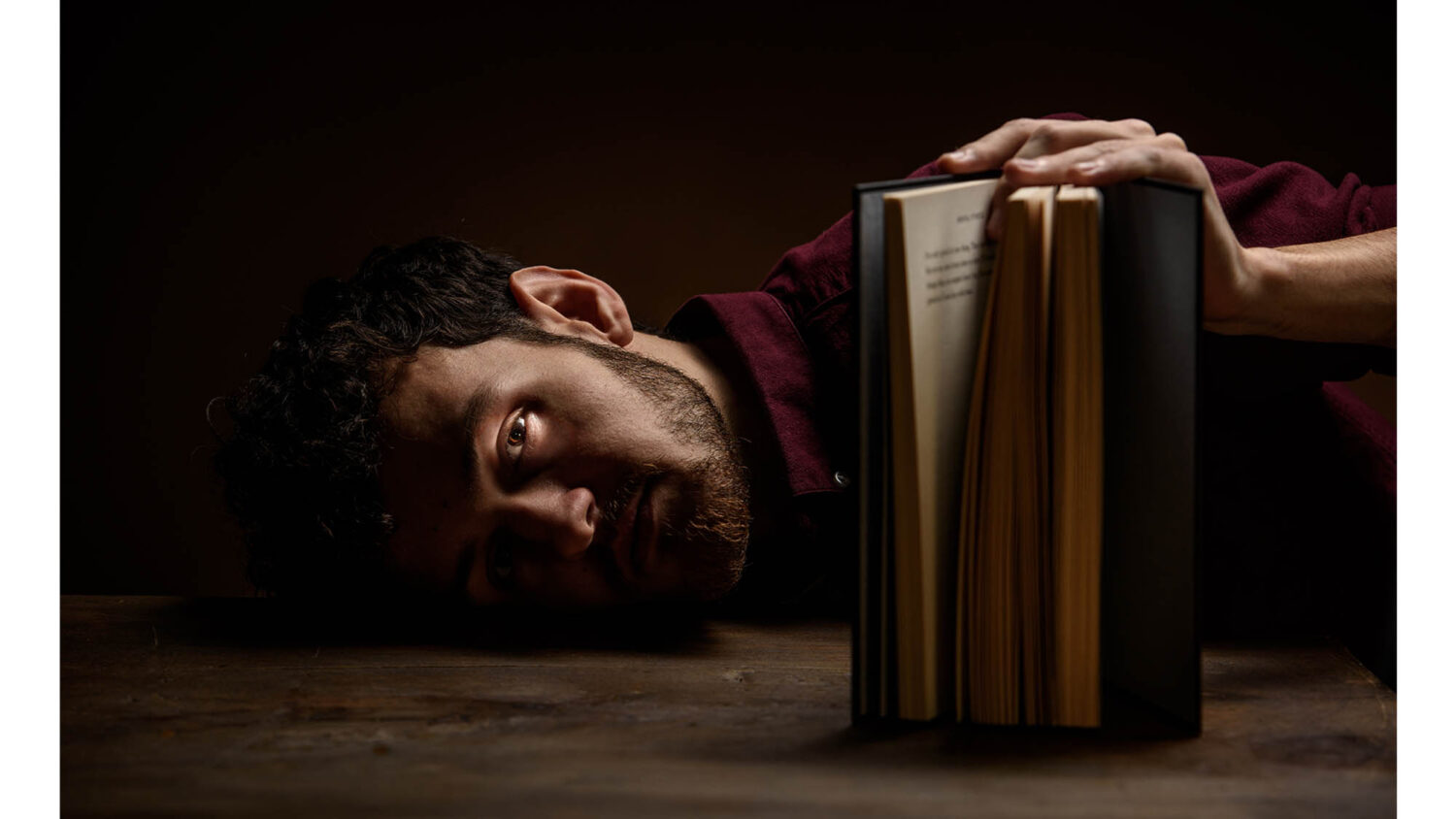 Portrait photography of young man holding book laying on desk